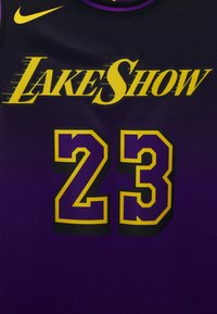 Mustapaita, jossa lukee "LAKE SHOW" keltaisella skriptillä, numero "23" lihavoinnilla violetissa ja keltaisessa reunanäytössä, ja Nike-logo olalla.