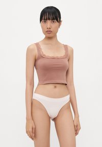 Bruine korte tanktop met kantafwerking, gecombineerd met lichtroze bikinionderbroek. Glad katoenmateriaal, eenvoudig ontwerp en aansluitende pasvorm.