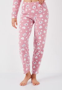 Pantaloni de pijama din fleece roz, cu un model de urși cartoon și inimioare, având o textură ribbed și o talie elastică.