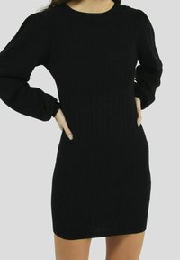 Robe noire en tissu doux à côtes, dotée de longues manches bouffantes et d'un col rond. La coupe est ajustée, mettant en valeur la silhouette.