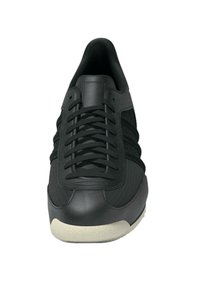 Schwarze Sneakers mit einer glatten Lederspitze, Obermaterial aus Mesh, flachen schwarzen Schnürsenkeln und einer strukturierten Sohle. Schlankes Profil und minimalistisches Design.