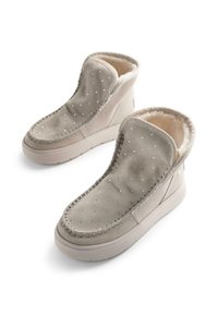 Botines beige de ante, con forro de falso pelo suave, costuras decorativas y strass incrustados en la parte superior.