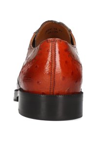 Zapato de vestir para hombre en cuero marrón pulido con suela negra, visto desde el talón, mostrando costuras detalladas y marcas de tamaño en el interior.