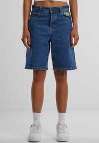 Dunkelblaue Denim-Shorts, mit geradem Schnitt, zwei Fronttaschen und einem Markenlogo-Patch auf der linken Tasche.