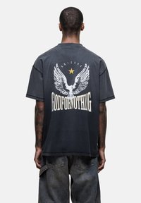 Zwarte oversized t-shirt met een grafische print op de achterkant van een adelaar en de tekst "GODFORNOTHING." Korte mouwen en een ontspannen pasvorm.