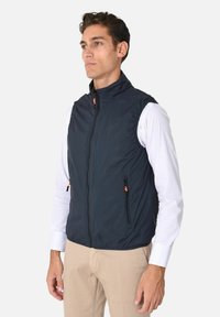 Gilet senza maniche blu navy con colletto alto, zip frontale e due tasche laterali con zip dotate di tiranti arancioni, realizzato in materiale leggero.