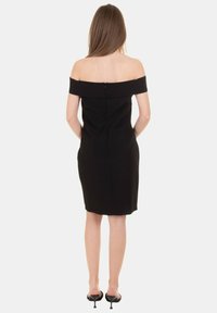 Vestito nero scollato sulle spalle con design aderente, texture liscia, taglio al ginocchio e cerniera nascosta sul retro.