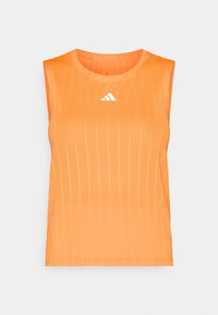 Πορτοκαλί αθλητικό τοπ χωρίς μανίκια με κάθετη ριμπ υφή, στρογγυλή λαιμόκοψη και λευκό λογότυπο Adidas στο στήθος. Ελαφρύ, αναπνέον ύφασμα.