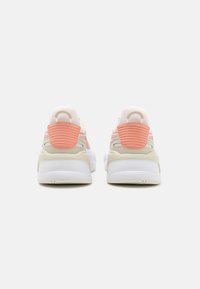 Adidași albi și piersici cu un toc texturat și un model din plasă, având o talpă groasă, în contrast, și un design unic al panoului din spate.