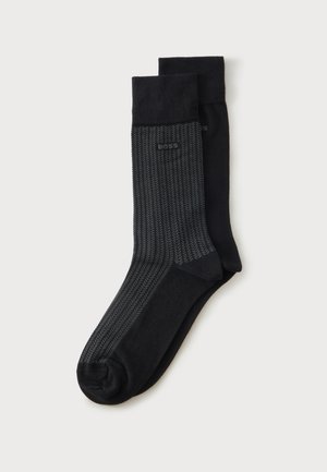Deux paires de chaussettes noires, une noire unie et une avec un motif chevron gris foncé et le logo "BOSS" près du bord-côte.