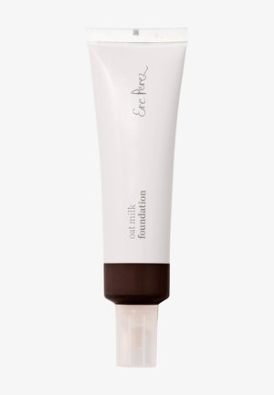 Fond de teint au lait d'avoine en tube compressible, avec une section supérieure blanche comportant le logo et du texte, et une section inférieure marron avec une base transparente.