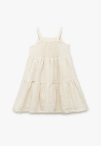 Lys beige kjole med tynde stropper, smocket overdressing og en lagdeling i skørterne. Lavet af tekstureret stof med et blødt, flydende udseende.