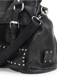 Bolso de mano de cuero negro con acentos de remaches, acabado texturizado, correa ajustable y detalles en hardware plateado. Parche de logo distintivo visible en el lateral.