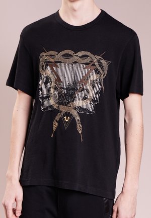 Czarny t-shirt z motywem złoto-brązowego węża oplecionego wokół trójkątnego wzoru z dwoma lustrzanymi czaszkami skierowanymi na zewnątrz.