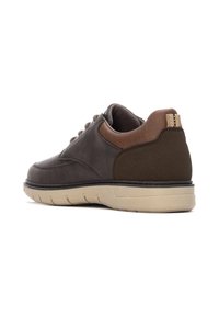 Zapatillas de cuero marrón, con una parte superior lisa, acentos de tela marrón en contraste, suela de goma beige y un refuerzo en el talón para mayor soporte.