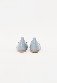 Chaussures en cuir bleu clair avec une texture matelassée, bout rond, petit talon et lacets décoratifs à l'avant. Fini lisse et design minimal.