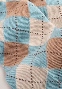 Tissu texturé présentant un motif argyle bleu, beige et marron clair avec des coutures marron. La surface a une apparence tissée.