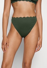 Parte de baixo de bikini de cintura alta em verde escuro, com um padrão texturizado e bordas recortadas, oferecendo um ajuste confortável e um tecido suave.