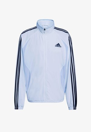 Witte atletische jas met marineblauwe drie-strepen ontwerp op de mouwen, hoge kraag, ritssluiting en lichtgewicht materiaal. Voorzien van Adidas-logo.