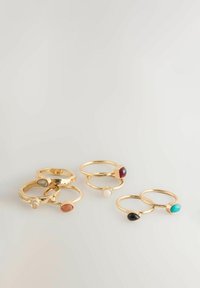 Set mit sechs goldenen Ringen, die verschiedene Edelsteine enthalten: rot, türkis, schwarz, weiß und orange. Die Ringe haben glatte und strukturierte Oberflächen.