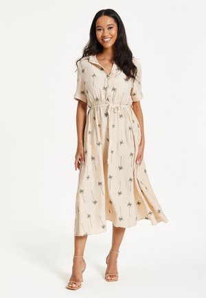 Beige, short-sleeved midi dress with palm tree print. Features a collar, button-down front, and cinched waist with a drawstring. Smooth texture.