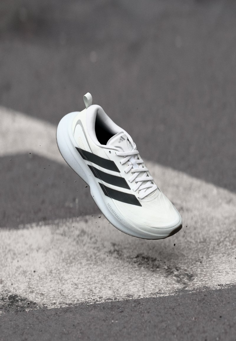 Λευκό αθλητικό παπούτσι με μαύρες και γκρι λεπτομέρειες, με υφασμένο άνω μέρος, κλείσιμο με κορδόνια και ελαφρύ, μαλακό πέλμα.