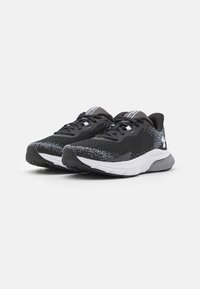 Zwarte sportieve schoenen met een geprofileerde mesh bovenkant, witte tussenzool en een rubberen buitenzool met patroon. Voorzien van zwarte veters en merkaccenten.