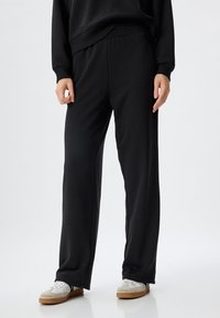 Schwarze Sweatpants mit lässigem Schnitt und elastischem Bund. Hergestellt aus glattem Stoff, mit seitlichen Taschen und geradem Bein design.