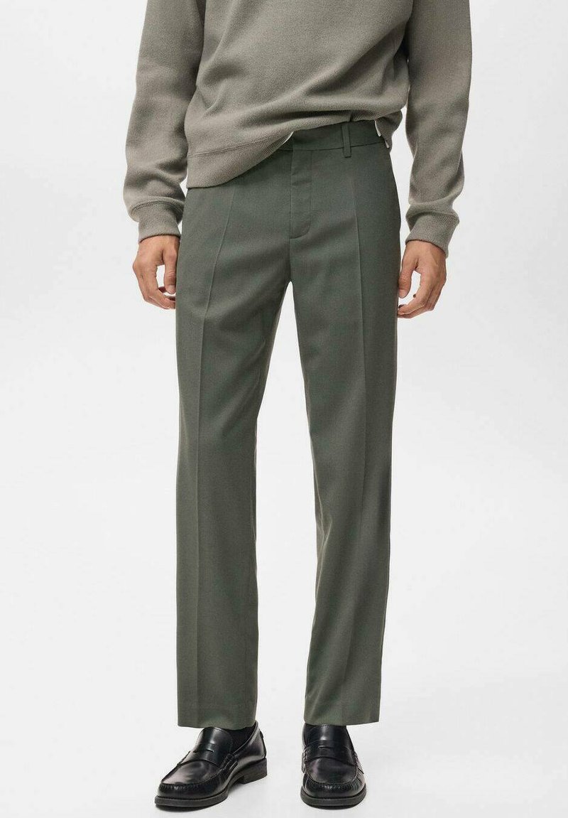 Pantalones verde oliva de corte recto con una textura suave, que cuentan con pliegues frontales y una cinturilla clásica. Combinados con un suéter gris y zapatos negros.