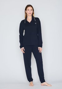 Polo de manga larga de color navy con ribete blanco y logo, acompañado de pantalones tapered a juego. Tejido suave, ajuste relajado y puños acanalados.
