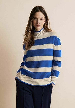 Pull rayé bleu et crème avec un col et un ourlet côtelés. Fabriqué en tissu doux, il dispose de manches longues et d'une coupe surdimensionnée.