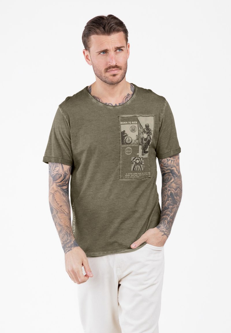 Camiseta de algodón verde oliva con escote redondo y mangas cortas. Presenta un estampado gráfico en la parte delantera, resaltando un tema de motocicletas.