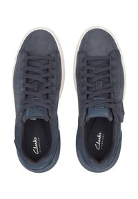 Mörkblå mockaskor med en slät yta, som har sex öglor, platta snören, perforerade detaljer och en vit gummisula.