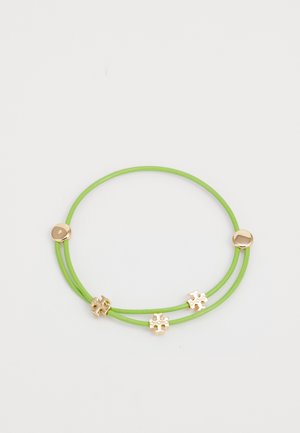 Grøn gummiarmbånd med tre dekorative accentuer i guldtonet farve med puslespilsdesign og en glat, blank finish.