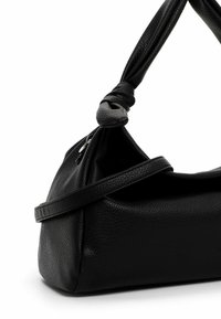 Must tekstuuriga nahast õlakott sõlmitud rihma detaili ja väikese nähtava hõbedase lukuosaga valgel taustal.