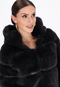 Sort faux fur jakke med en blød tekstur, oversized hætte og lynlåslukning. Har store, fyldige sektioner og en subtil glans.