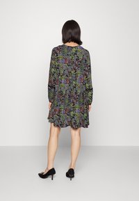 Vestido preto de mangas longas com padrão floral em verde, vermelho e roxo; saia rodada; usar com sapatos de salto pretos.