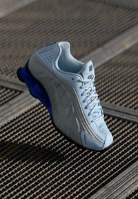 Nike bėgimo bateliai su šviesiai mėlynu tinkleliu, perforuotu paviršiumi ir tamsiai mėlynu guminio pado su ryškiu amortizavimu.