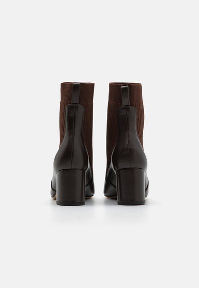 Stivali ankle in pelle marrone con un'asta in tessuto a maglia rigata, punta rotonda e tacco a blocco. Presenta asole per una facile vestibilità.