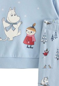 Jasnoniebieska bluza i spodnie z postaciami z Muminków. Miękka bawełniana tkanina, z nadrukowanymi wzorami zwierząt i zimowych krajobrazów.