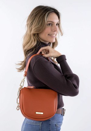 Brown leather crossbody bag with a rounded shape, featuring a gold hardware accent and a braided edge detail.