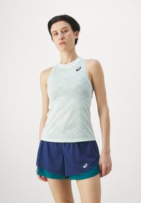 Lichtgroene tanktop met een diamantpatroon en een witte kraag, gecombineerd met marineblauwe shorts met groene accenten en een logo op de zoom.
