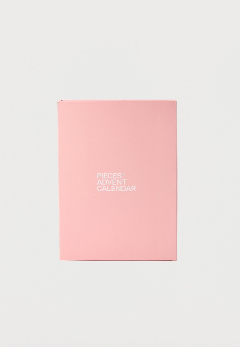 Ροζ κουτί ημερολογίου αντίστροφης μέτρησης από χαρτόνι με ματ φινίρισμα, με λευκό κείμενο που γράφει «PIECES ADVENT CALENDAR» στο κέντρο της πρόσοψης.