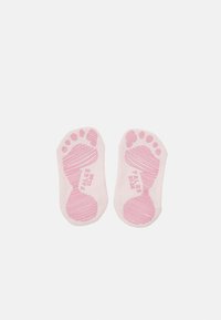 Calzini in cotone di colore rosa chiaro con impugnature in gomma a forma di piede sulla suola e testo in rilievo, progettati per migliorare la trazione.