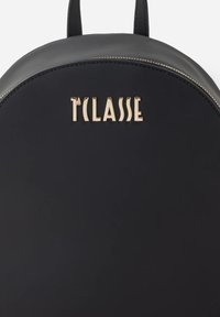 Zaino in pelle nera dalla forma arrotondata, con logo in rilievo color oro e dettaglio zip a contrasto lungo il bordo.