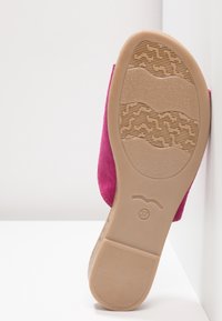 Chaussure en daim fuchsia avec une semelle en caoutchouc beige texturée présentant des motifs ondulés et un logo circulaire. Taille marquée 37.