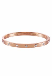Rose gold bangle bracelet featuring circular clear crystal accents, smooth polished surface, and engraved brand name on the inner edge.