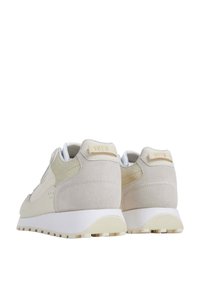 Beige suede sneakers with white rubber soles, featuring a textured back, subtle stitching, and a tag reading "1973" on the heel.