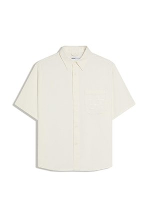Krémová košeľa s krátkym rukávom na zapínanie na gombíky, so špicatým golierom a jemným reliéfnym vzorom na ľavom hrudnom vrecku.