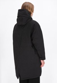 Sort puffjakke med h�ætte, der har en glat tekstur og en lang, oversized silhuet. Inkluderer knaplukninger foran og sideåbninger.